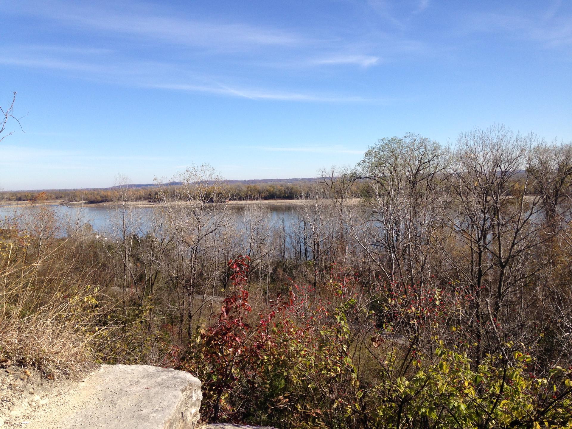 Scenic river view with autumn trees and a clear blue sky.