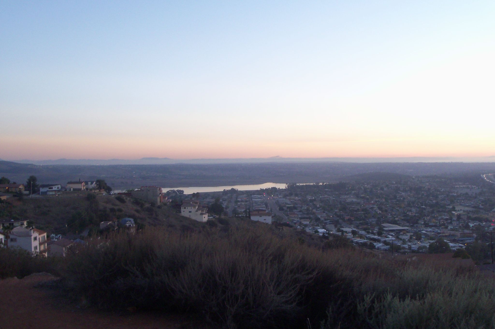 Expansive view of a town, lake, and hills under a serene, colorful twilight sky. - Dictionary Hill