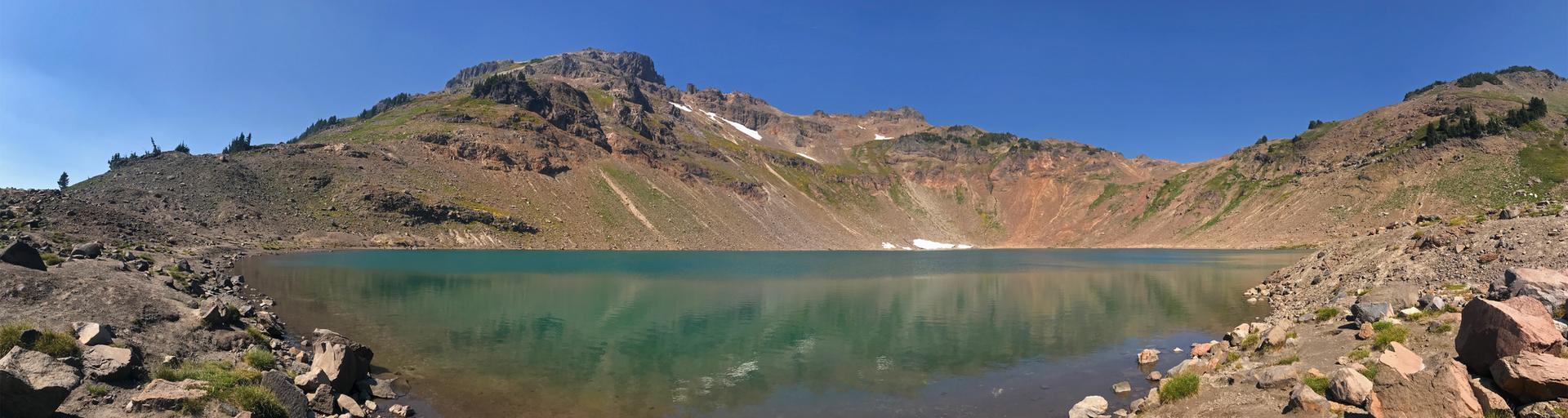 Panoramic view of a turquoise mountain lake surrounded by colorful, rocky slopes.