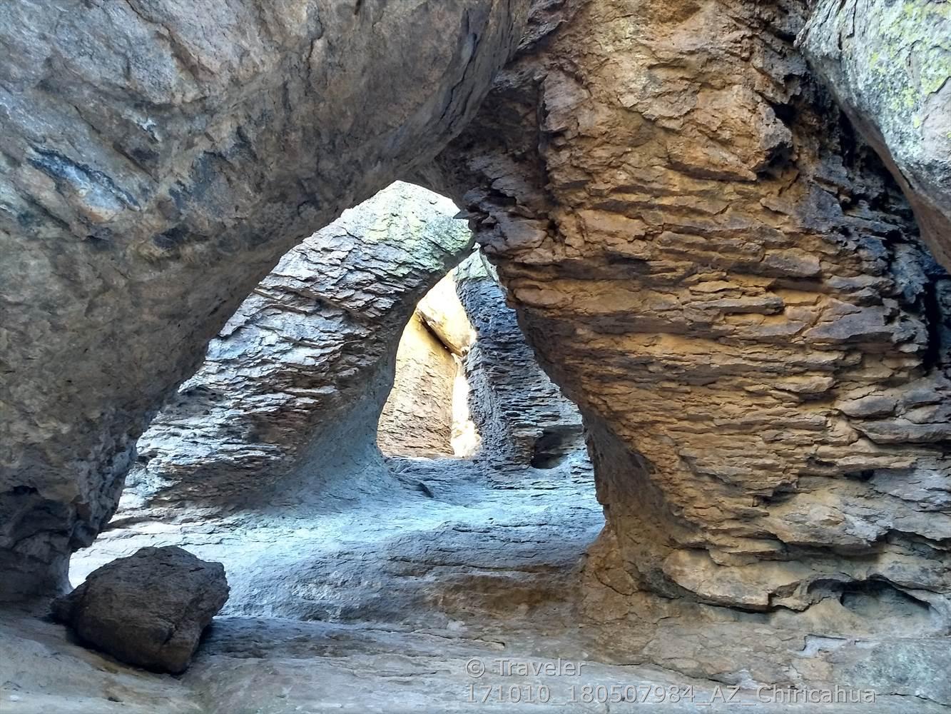 Natural rock arches forming a tunnel with light at the far end.