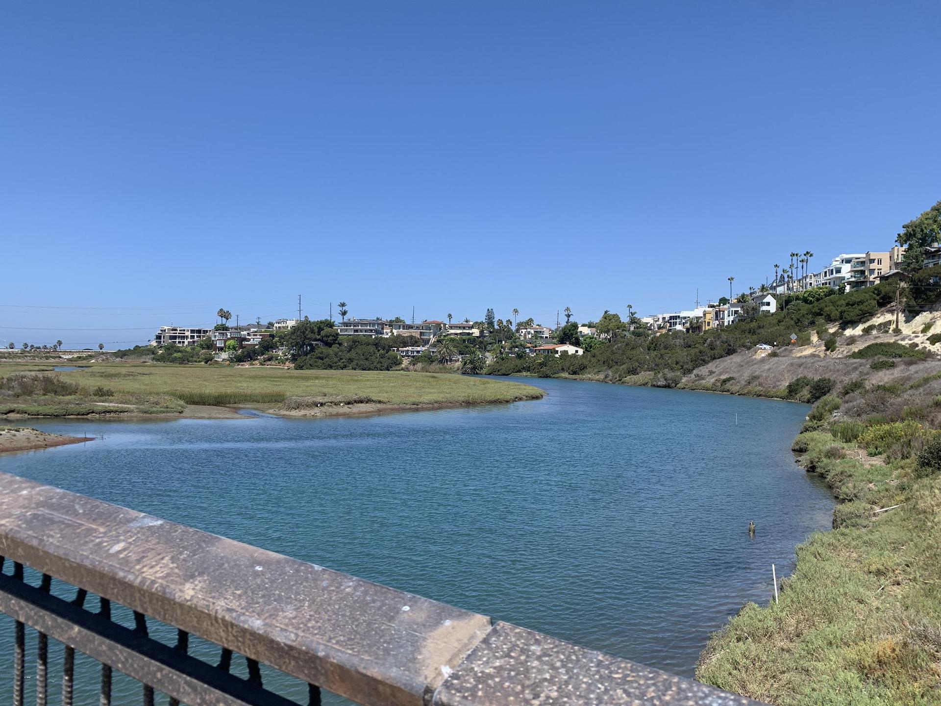 Blue water estuary with distant houses on hills, sunny day.