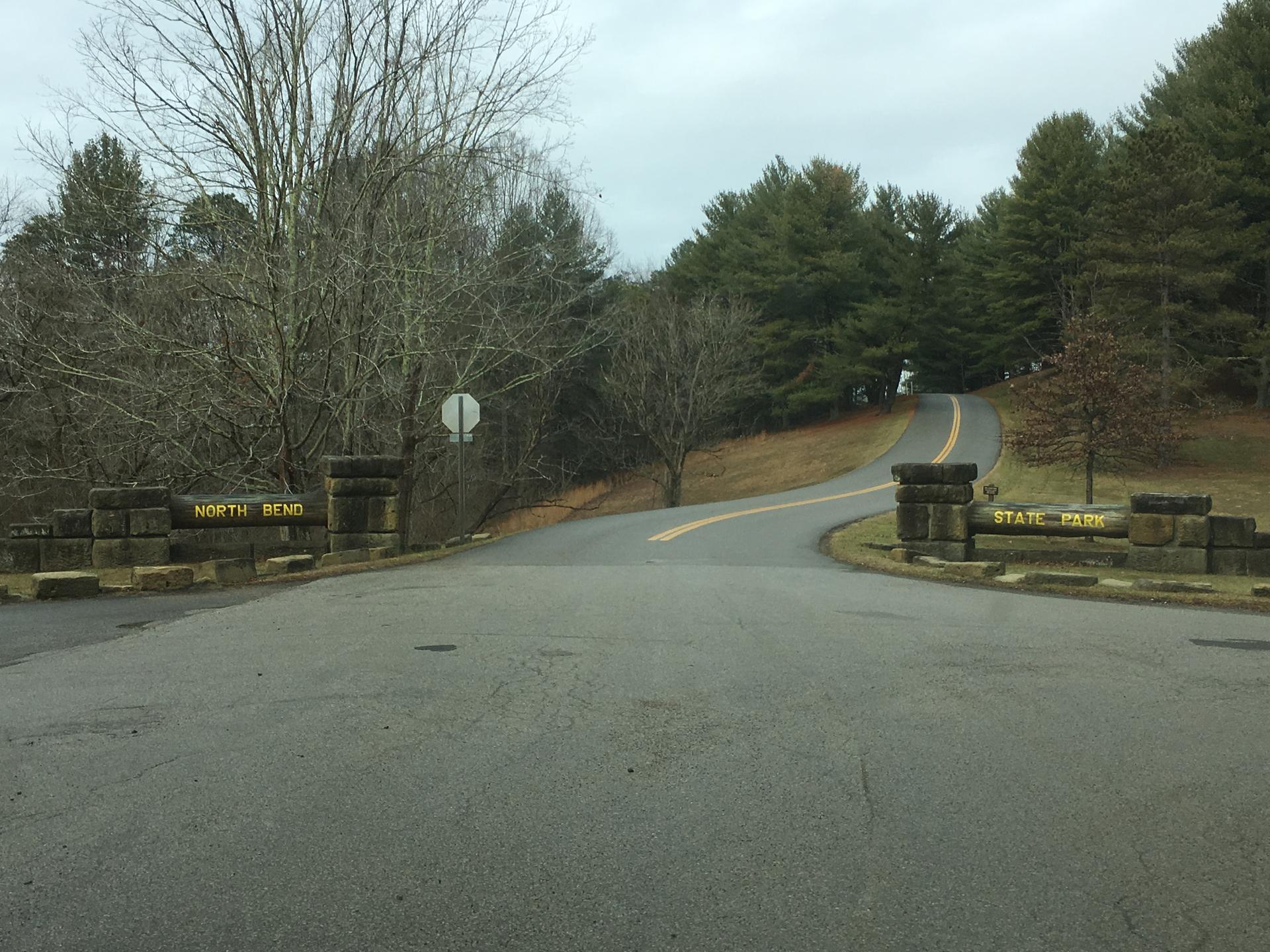A paved road entrance with stone pillars under an overcast sky.