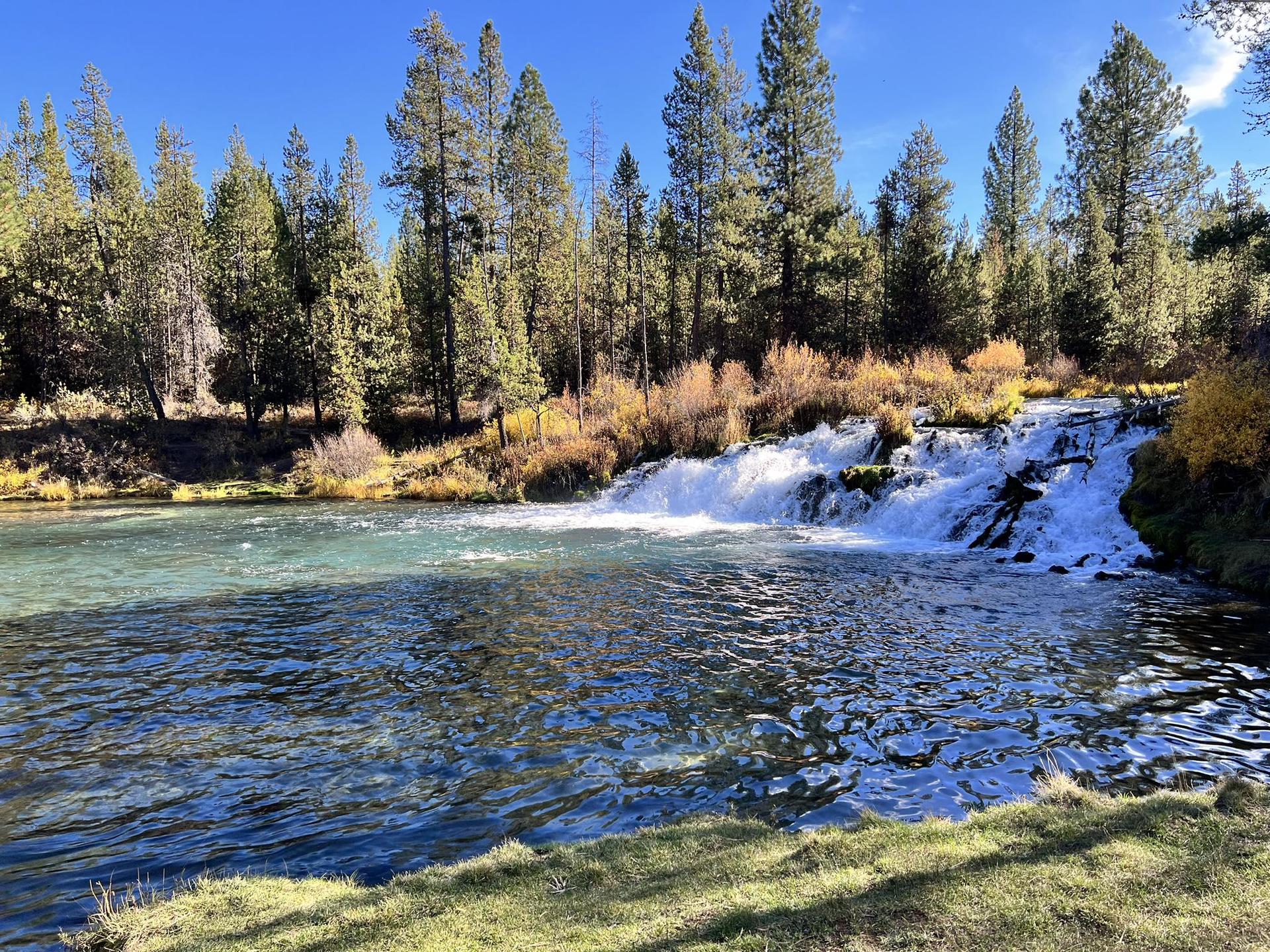 Bright sunny day with a clear river flowing into a waterfall.