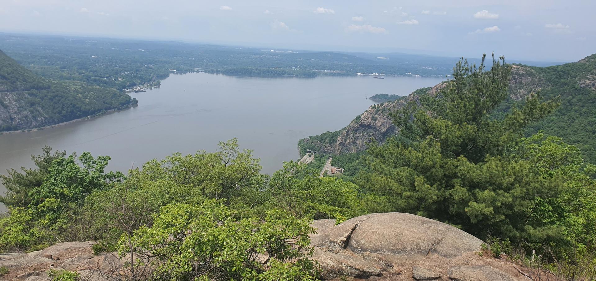 Overlook of a wide river and forested hills, with rocky foreground.