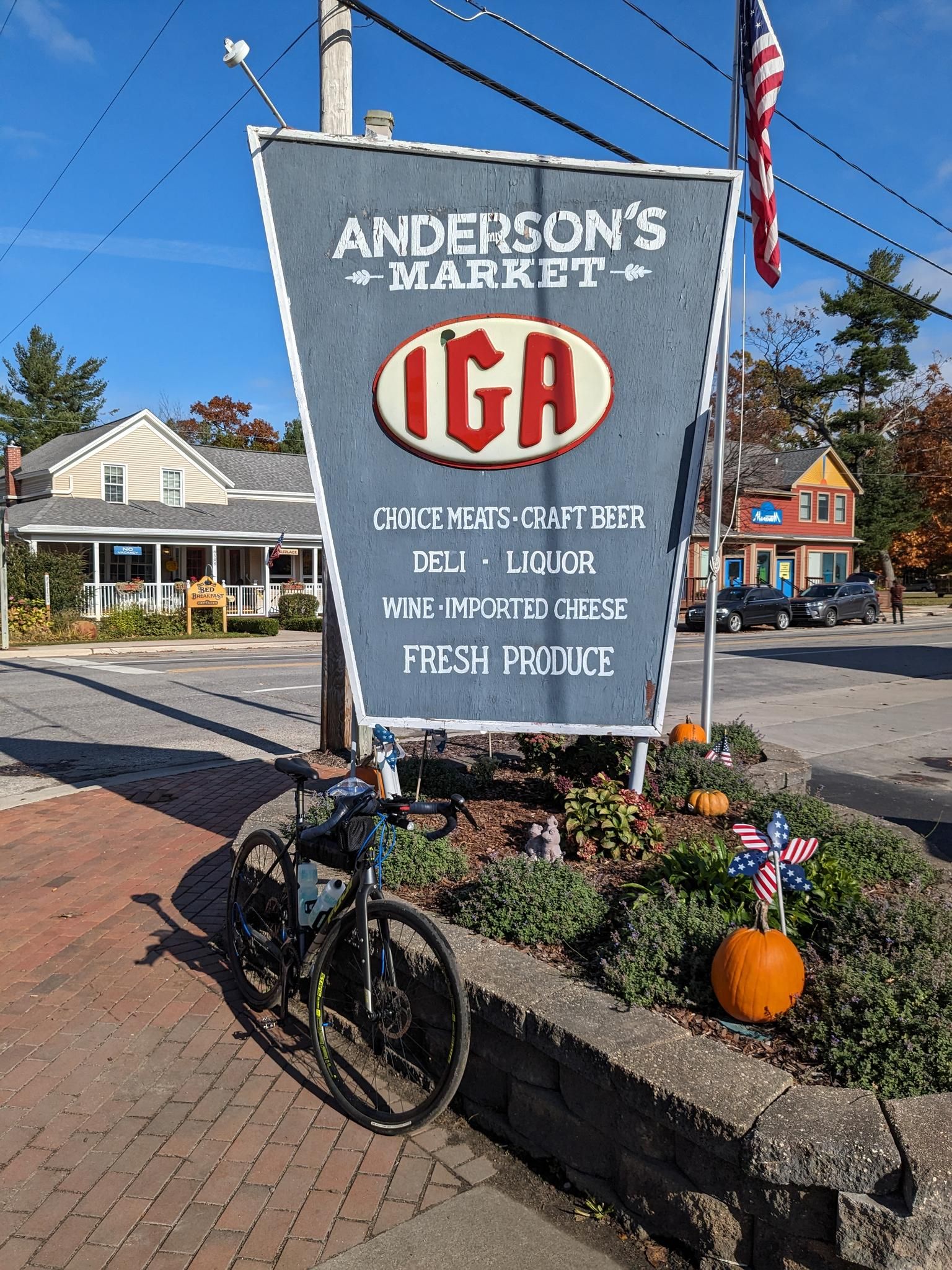 Bicycle parked by a market sign with autumn decorations on a sunny day. - Glen Arbor – Windy Moraine Trailhead loop from Empire