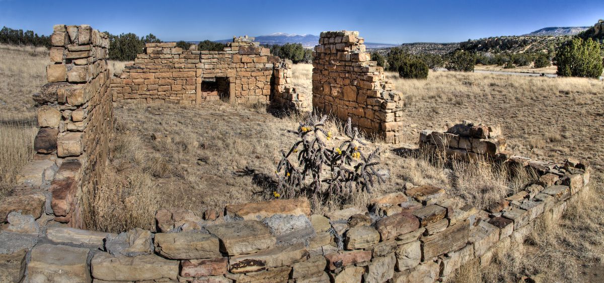 Ancient stone ruins stand in a dry, grassy field under a clear sky. - Sandstone Bluffs Trail