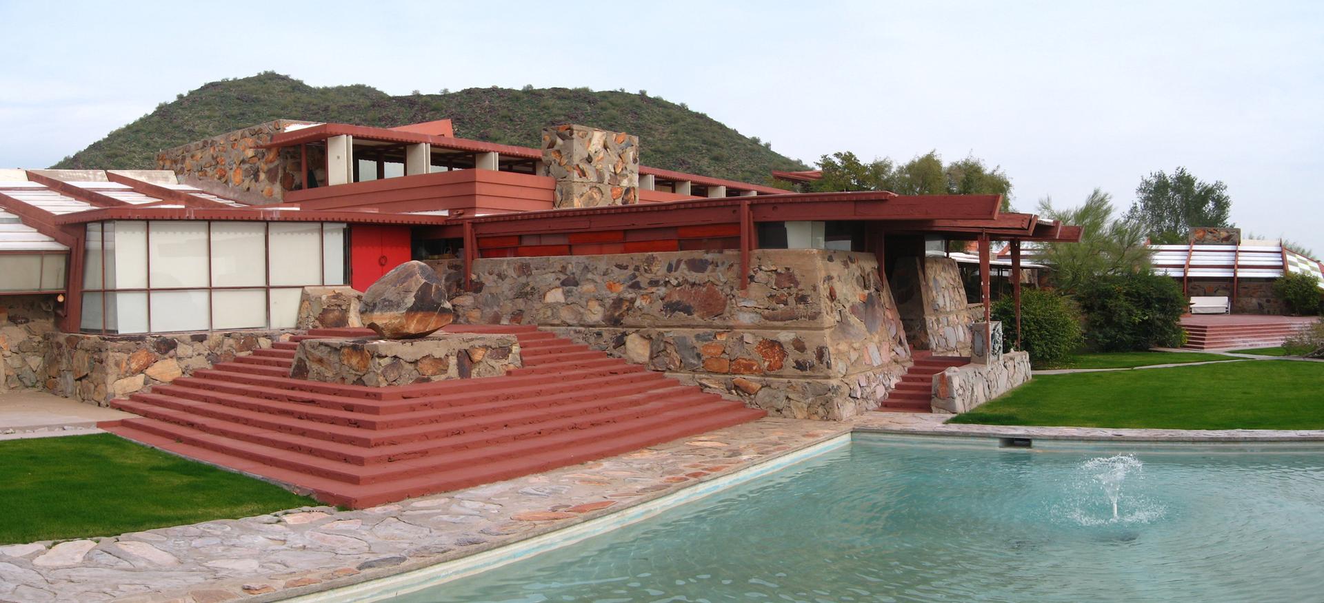 A large, multi-level building with a pool and distant hills.