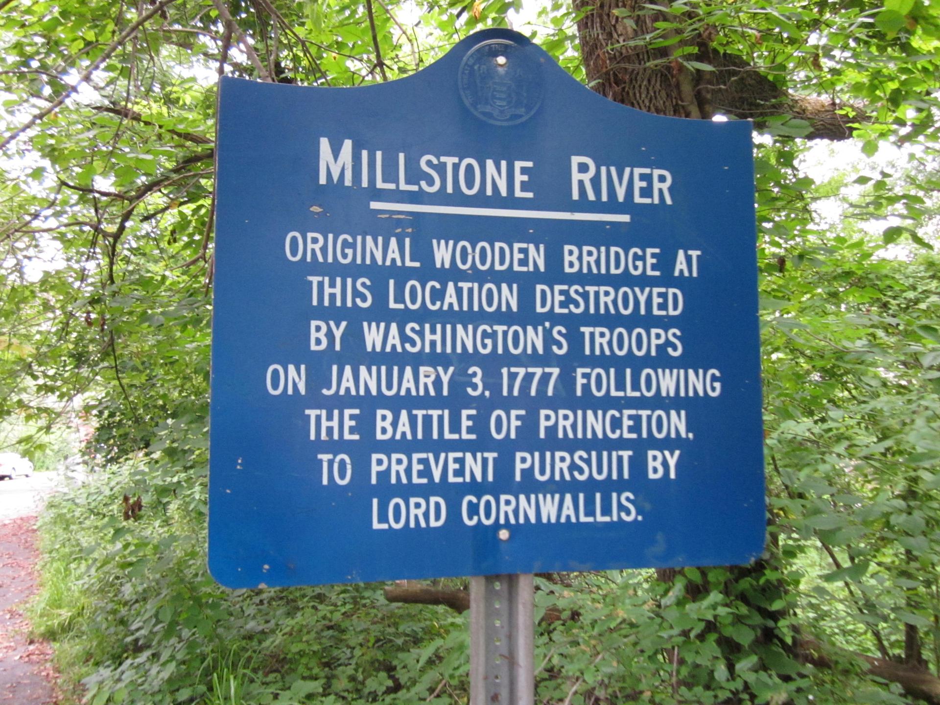 A blue historical marker sign surrounded by green foliage.