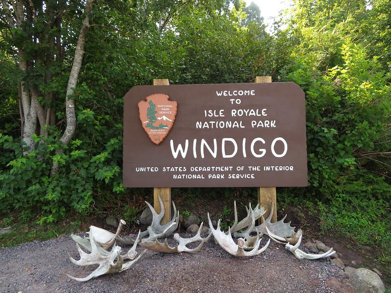 A wooden park sign with antlers and skulls displayed on the ground.