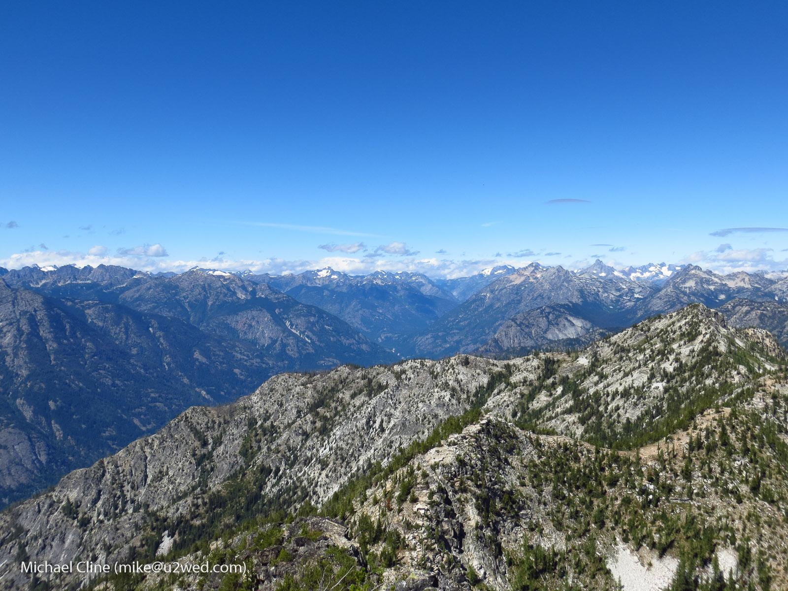 Expansive view of rugged mountain peaks under a clear blue sky.