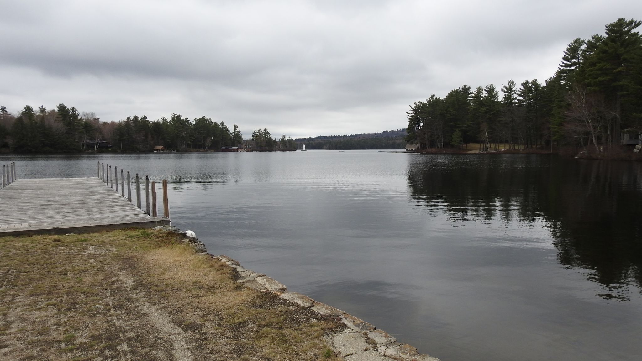 Wooden dock on calm lake, dense forests under overcast sky. - Lake Sunapee & Newport loop from Grantham