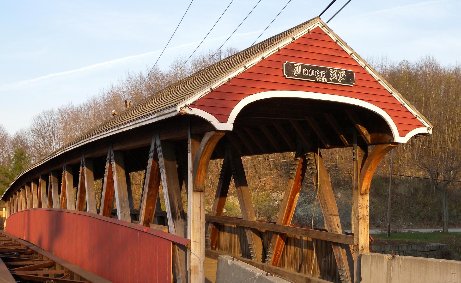 A red covered bridge bathed in warm, golden hour sunlight.