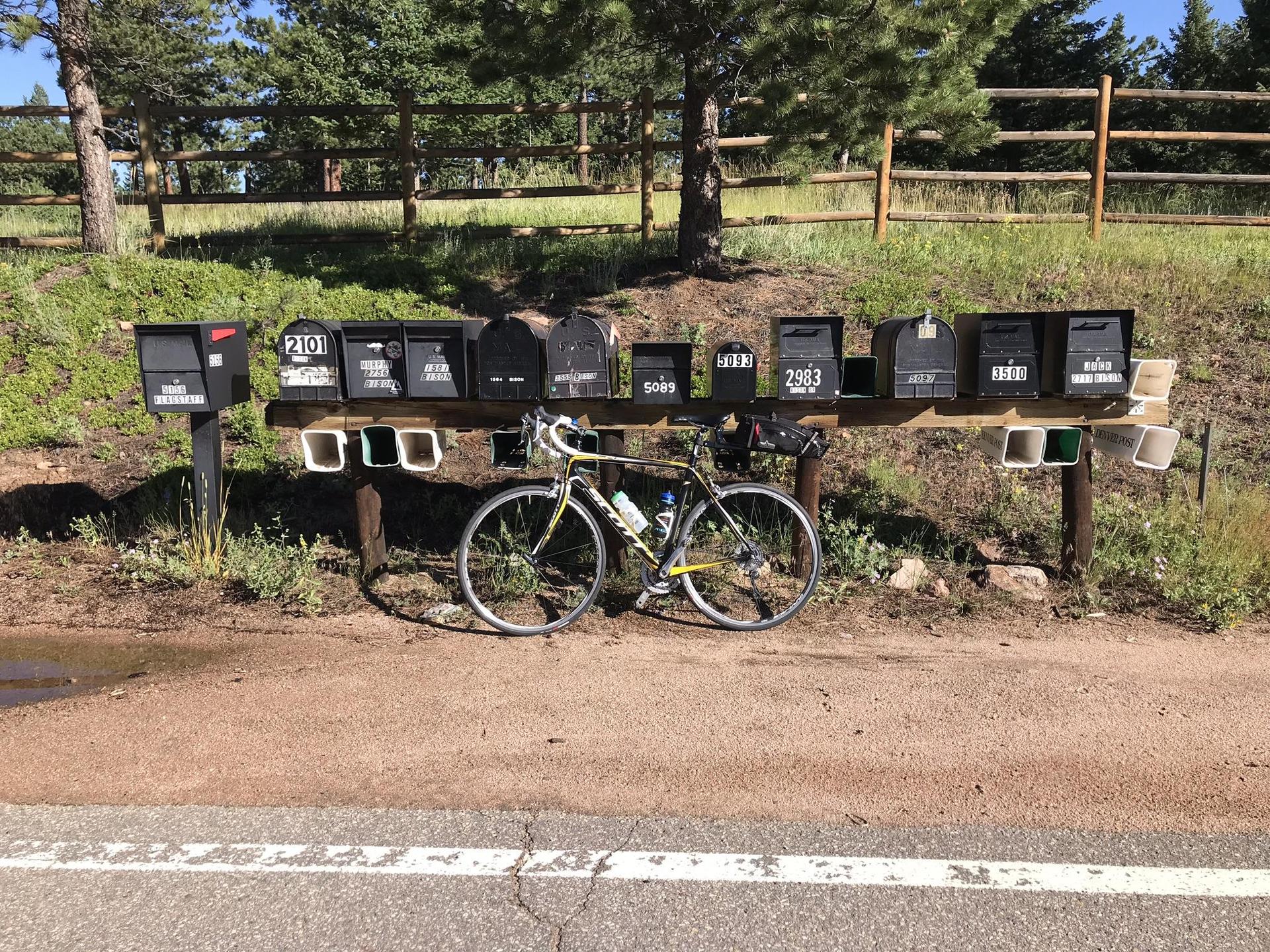 A bicycle parked beside a row of mailboxes on a sunny day.