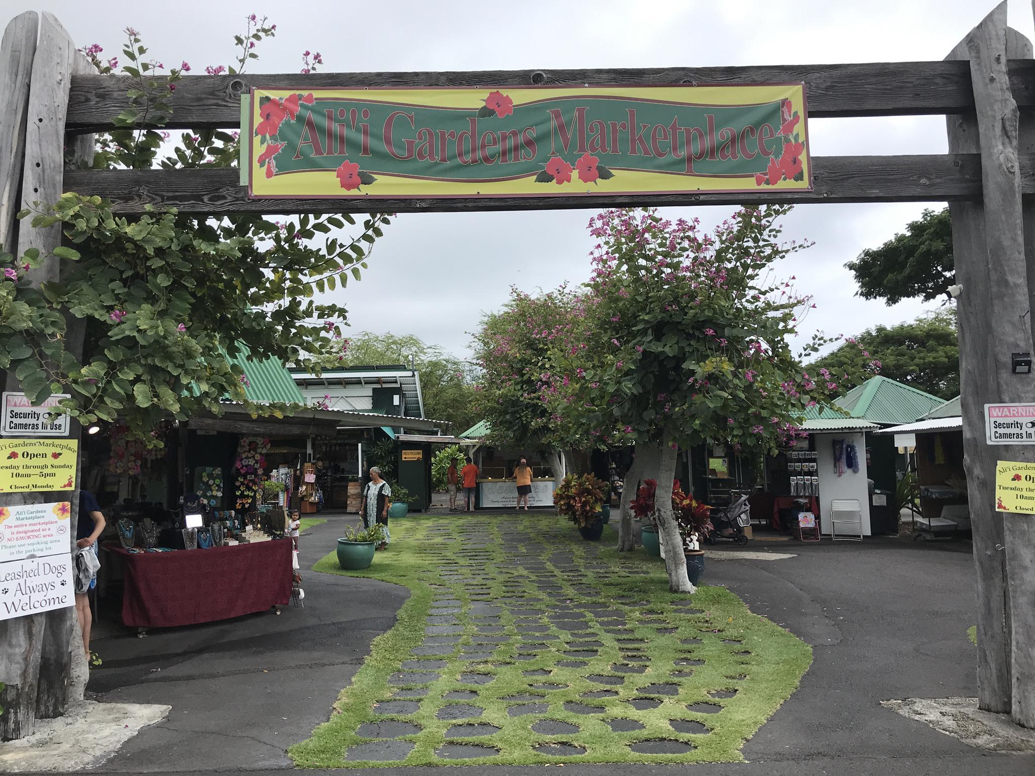 Wooden arch entrance to a bustling outdoor market on an overcast day.