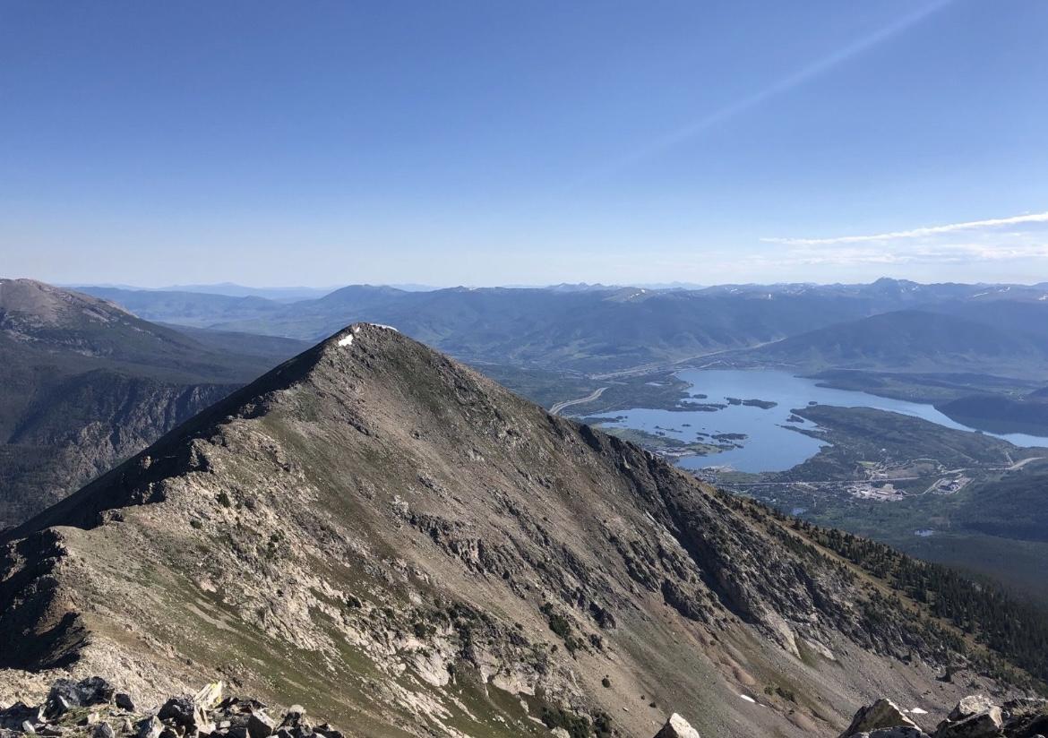 Sharp mountain peak overlooking a vast lake and valley on a clear day.