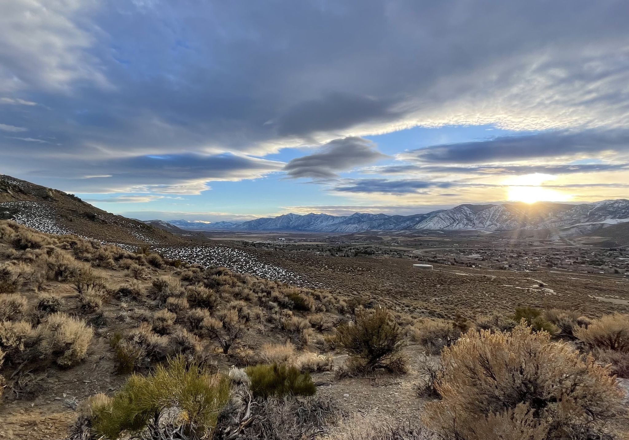 Sunset over a vast, arid valley with snow-dusted mountains and cloudy sky. - Mexican Ditch and Prison Hill Loop