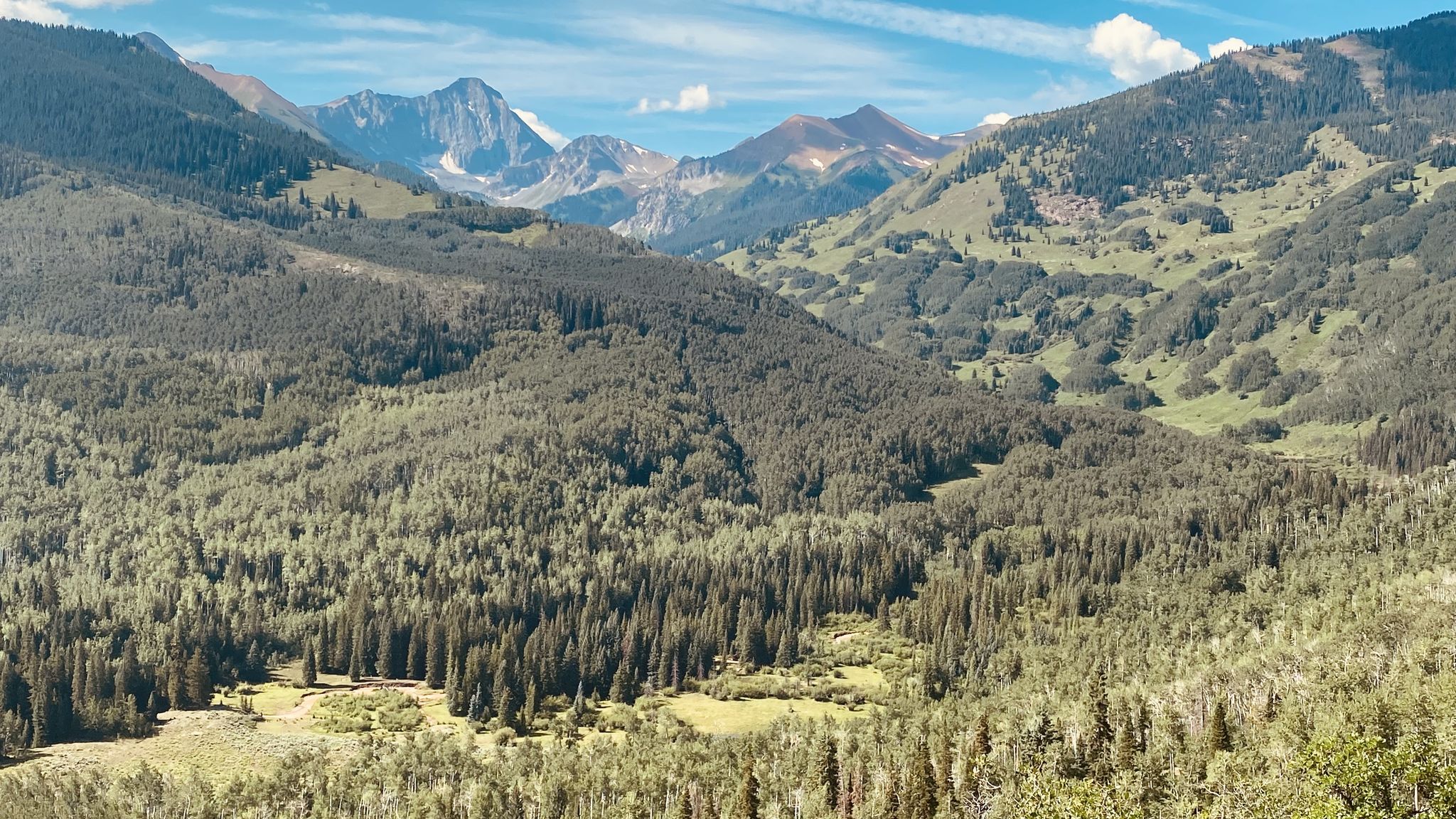 Vast mountain valley with dense green forests and distant peaks under a bright sky. - Capitol Peak via Capitol Ditch Trail