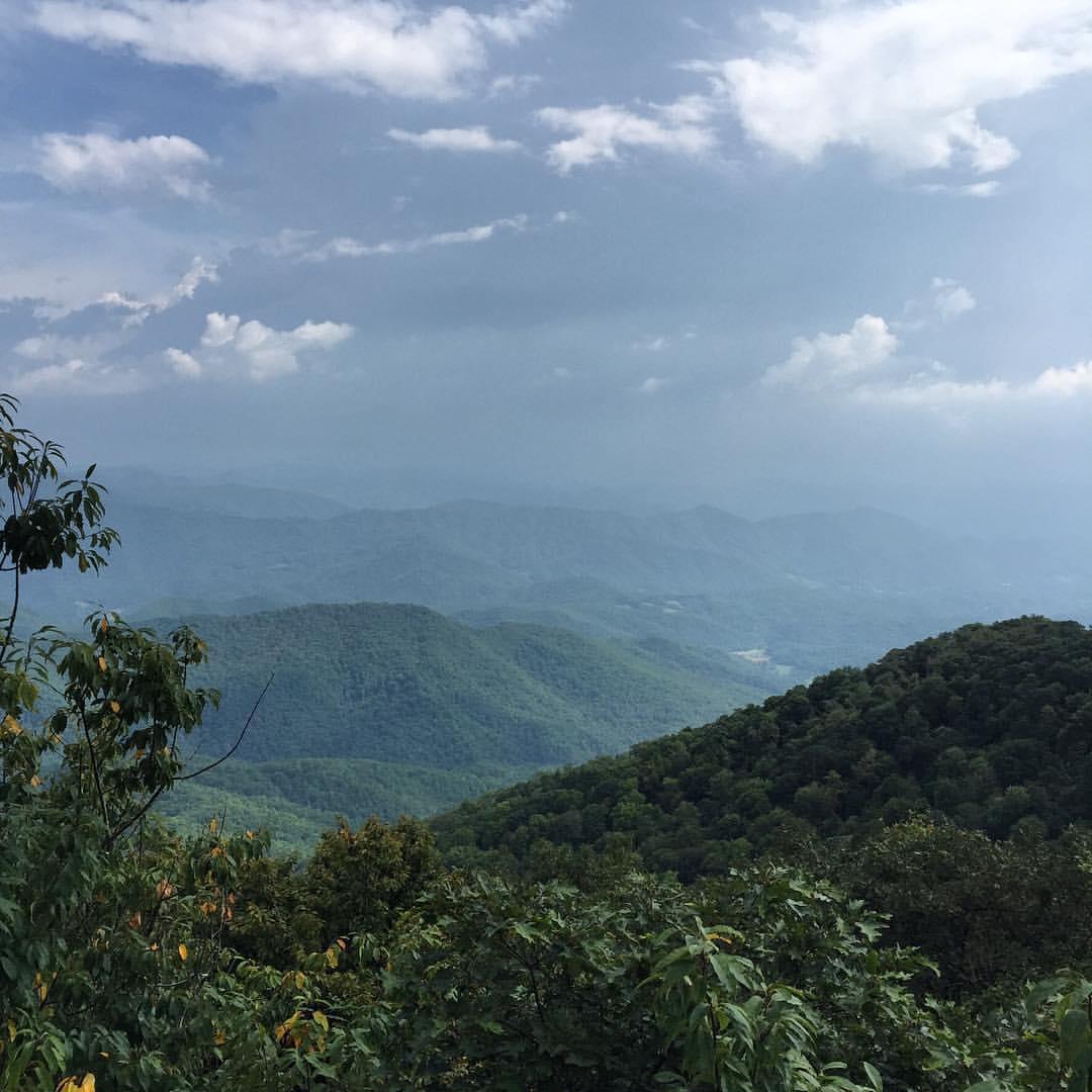 Expansive view of rolling green mountains under a dramatic, cloudy sky.