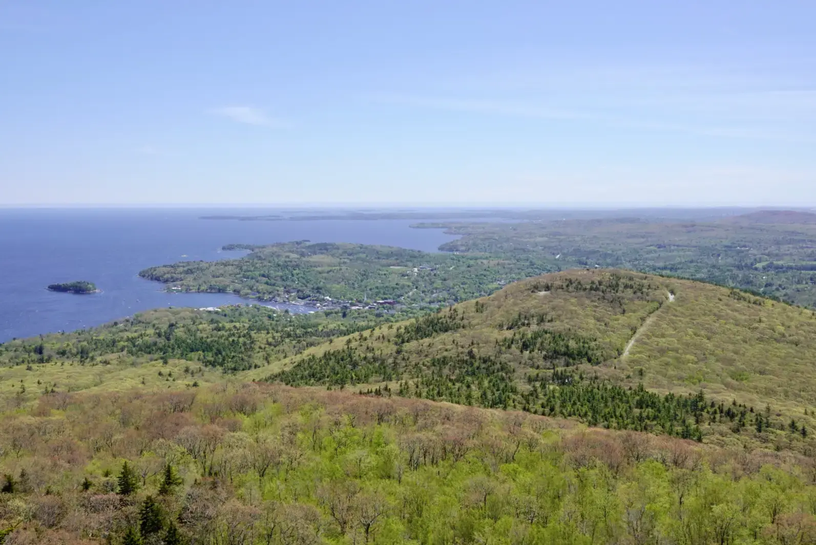 Aerial view of green hills, a town, and a large body of water.
