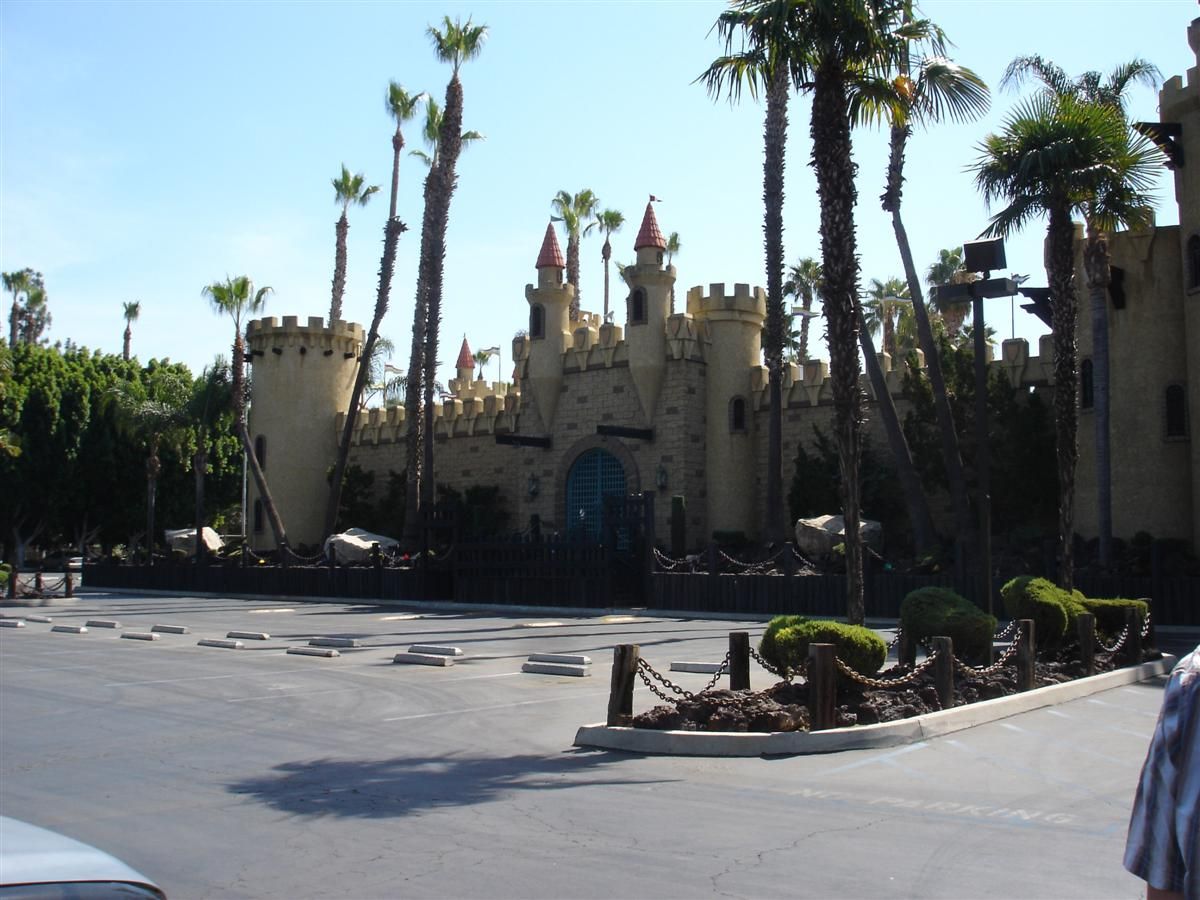 A large, tan castle-like building with palm trees under a clear sky. - Santa Ana River Trail to Castle Park loop