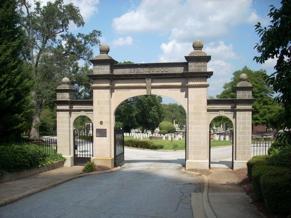 Large stone archway entrance to a cemetery on a bright, sunny day.