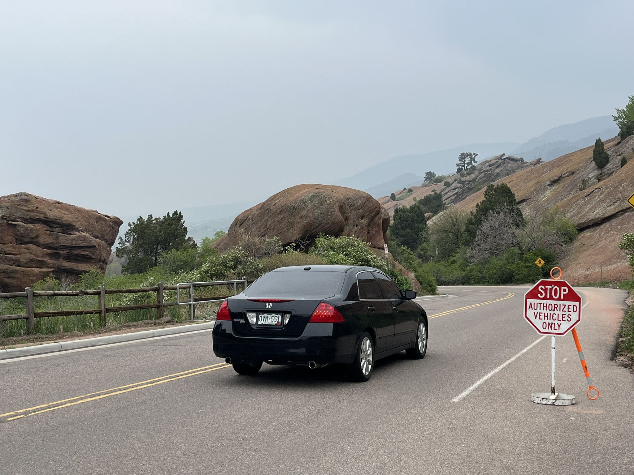 A black car drives on a winding road past large rock formations. - Red Rocks Park Scenic Road – Red Rocks View Point loop from Morrison
