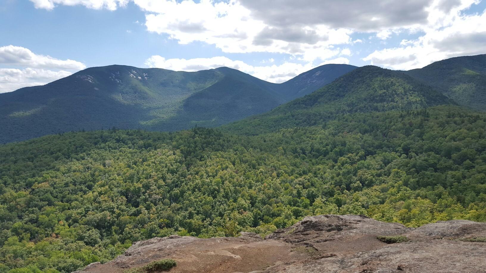 Panoramic view of lush green mountains under a partly cloudy sky.