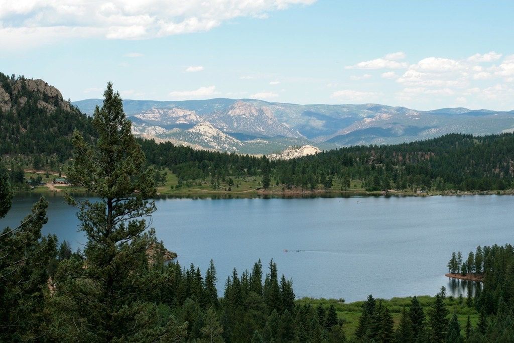 Expansive lake surrounded by green forests and distant mountains on a sunny day. - South Buffalo Creek, Wellington Lake, & Stoney Pass Road gravel loop