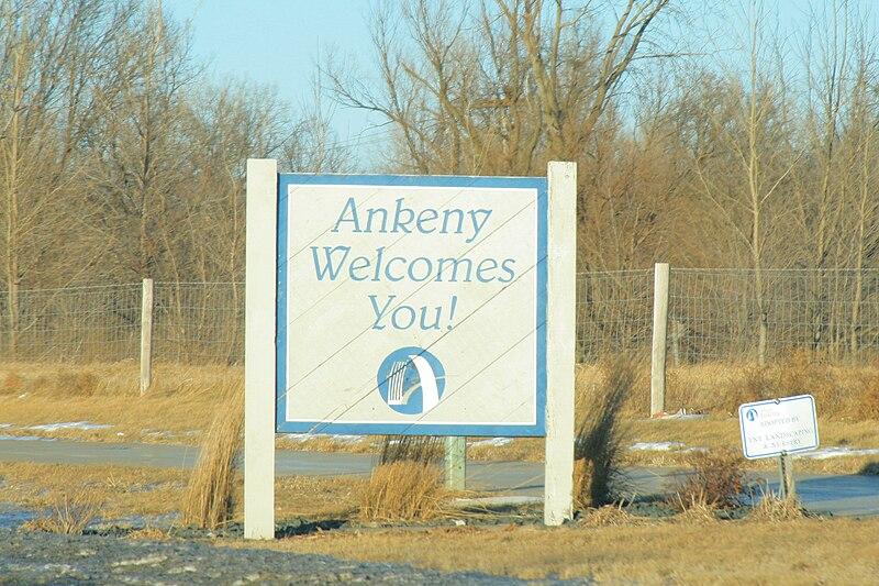 Welcome sign in a dry, grassy field with bare trees under golden light.