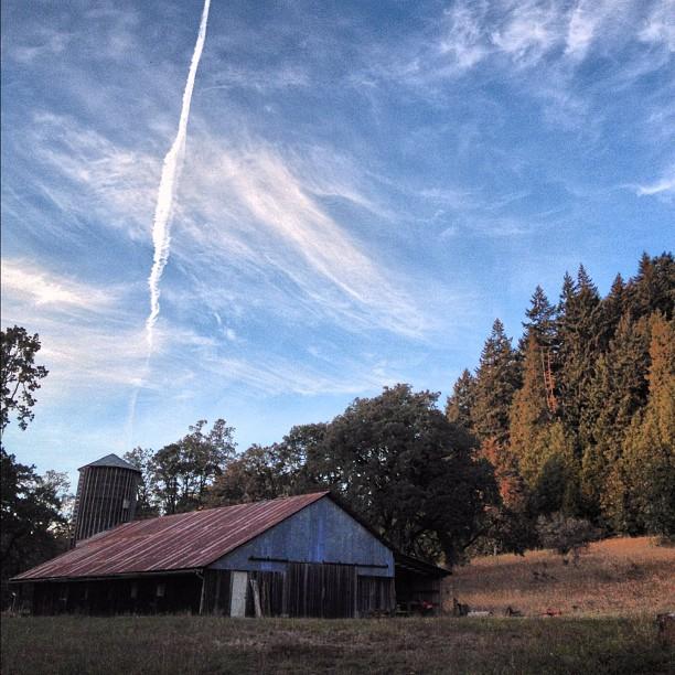 Old barn and silo under a dramatic blue sky with wispy clouds.