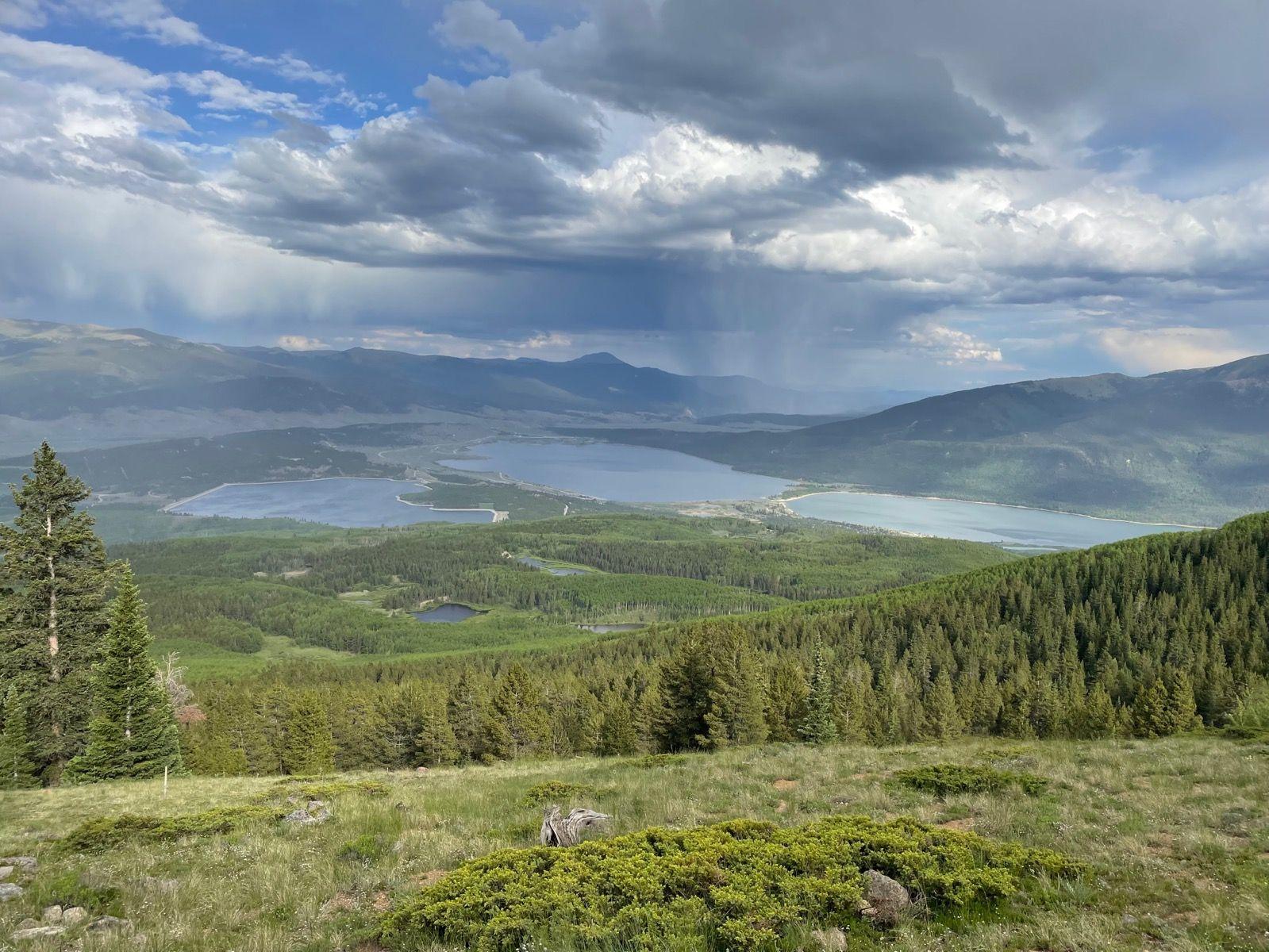 Panoramic view of multiple lakes and forests under a cloudy sky.