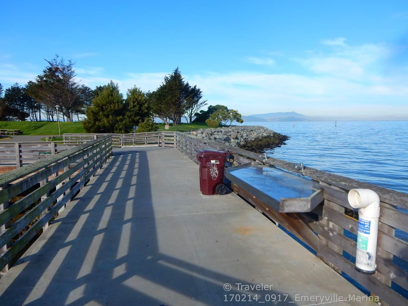 Wooden pier over calm bay water on a bright, clear day.