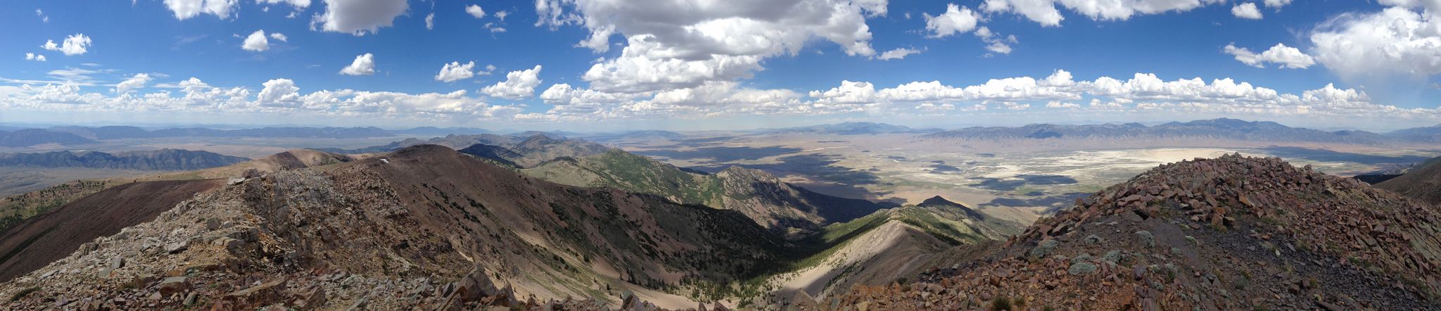 Panoramic view of rugged mountain peaks under a bright, cloudy sky. - North Schell Peak Trail