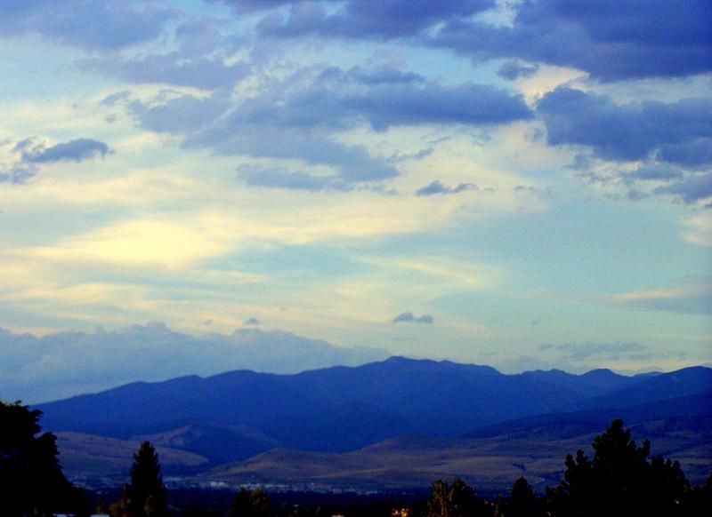 Distant blue mountains under a cloudy sky with warm evening light. - Miller Creek Road