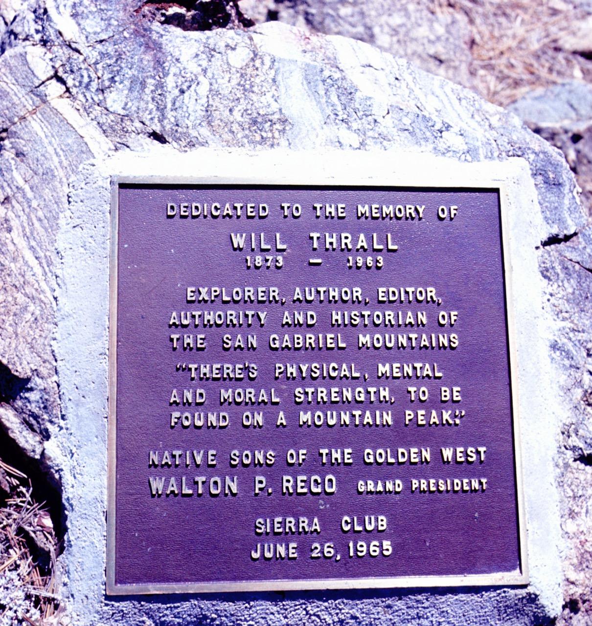 A bronze memorial plaque is affixed to a large, textured rock.