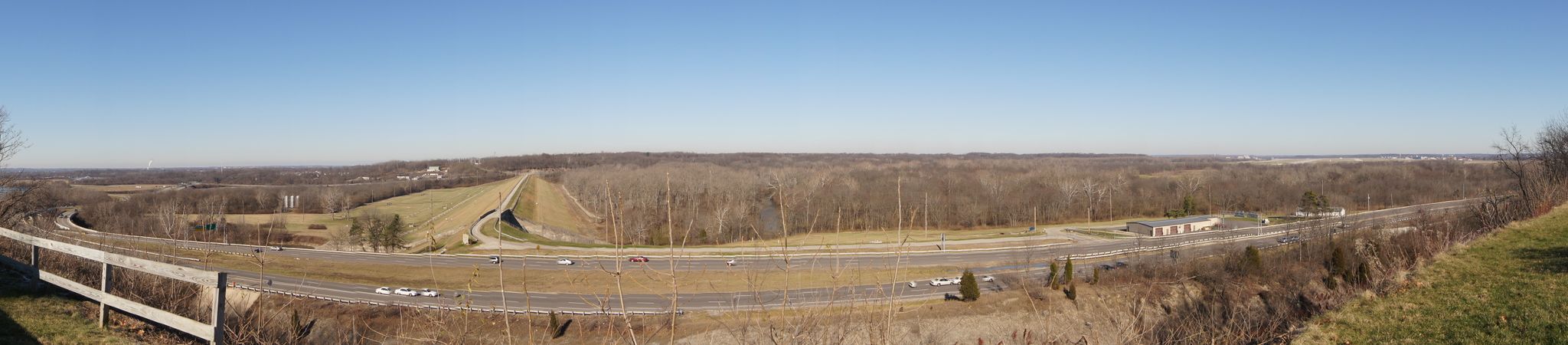 Panoramic view of a highway winding through a valley with bare trees under clear sky. - Huffman Prairie Bikeway