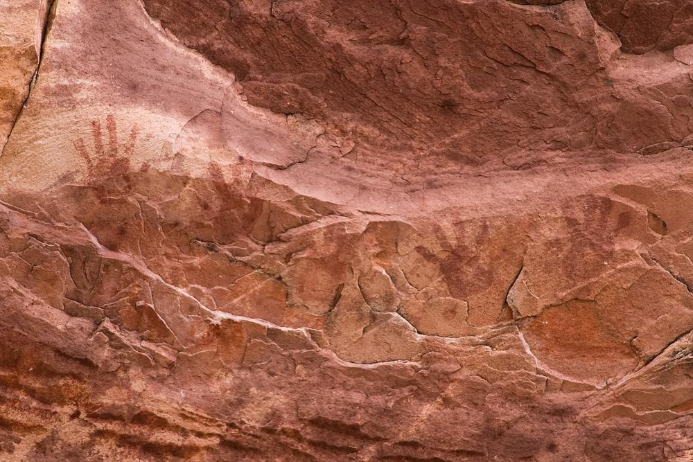 Close-up of red rock with ancient handprint pictographs and markings.