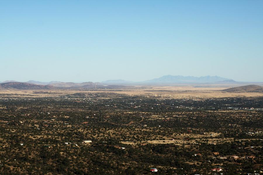 Vast, dry desert landscape with scattered vegetation and distant mountains under clear sky.