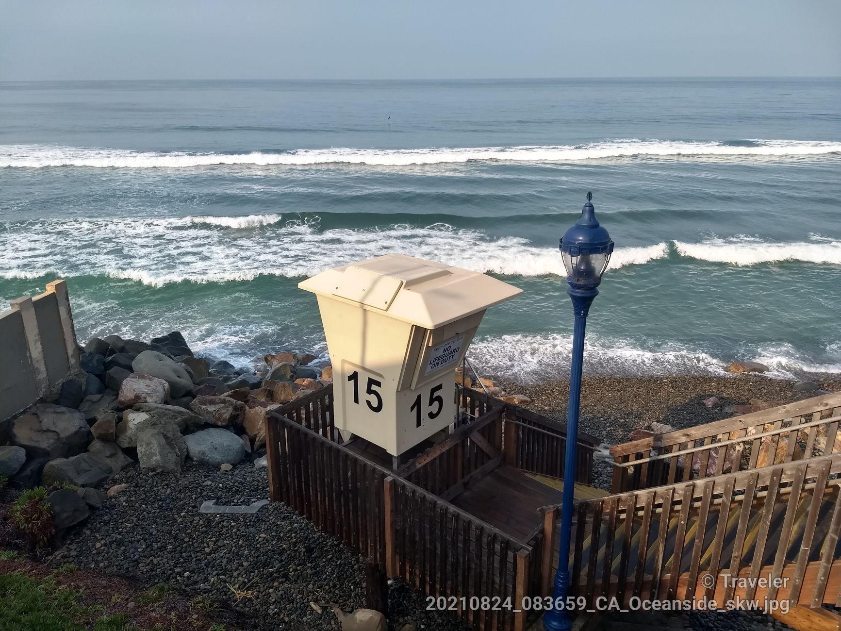 Lifeguard tower 15 on a rocky beach next to ocean waves.