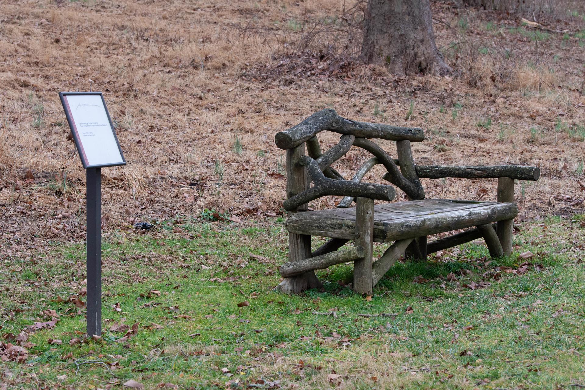 Rustic wooden bench next to an information sign in a natural setting.