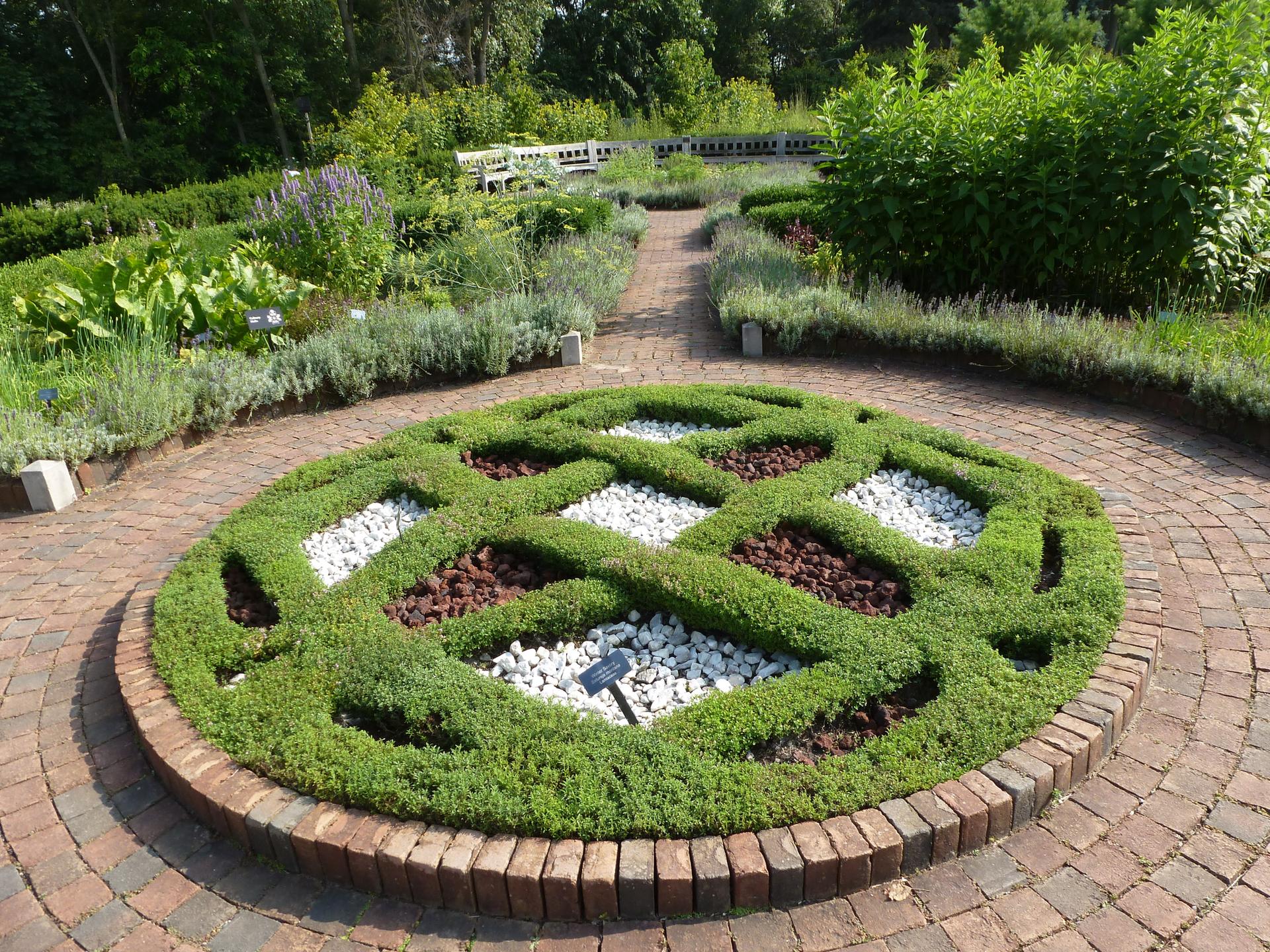 A circular garden bed with intricate green patterns and white stones.