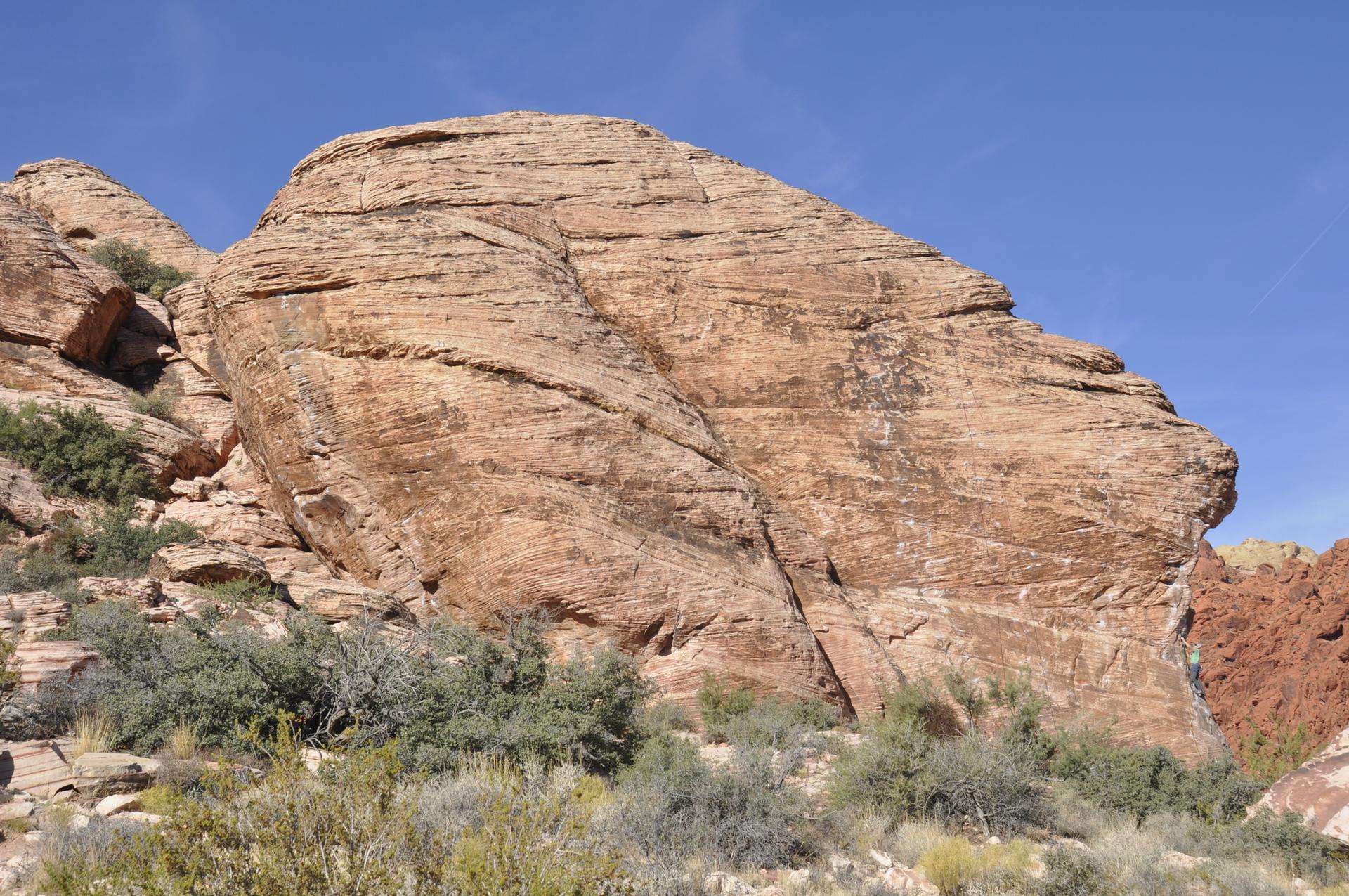 A large, textured red rock boulder dominates the foreground under a clear sky.