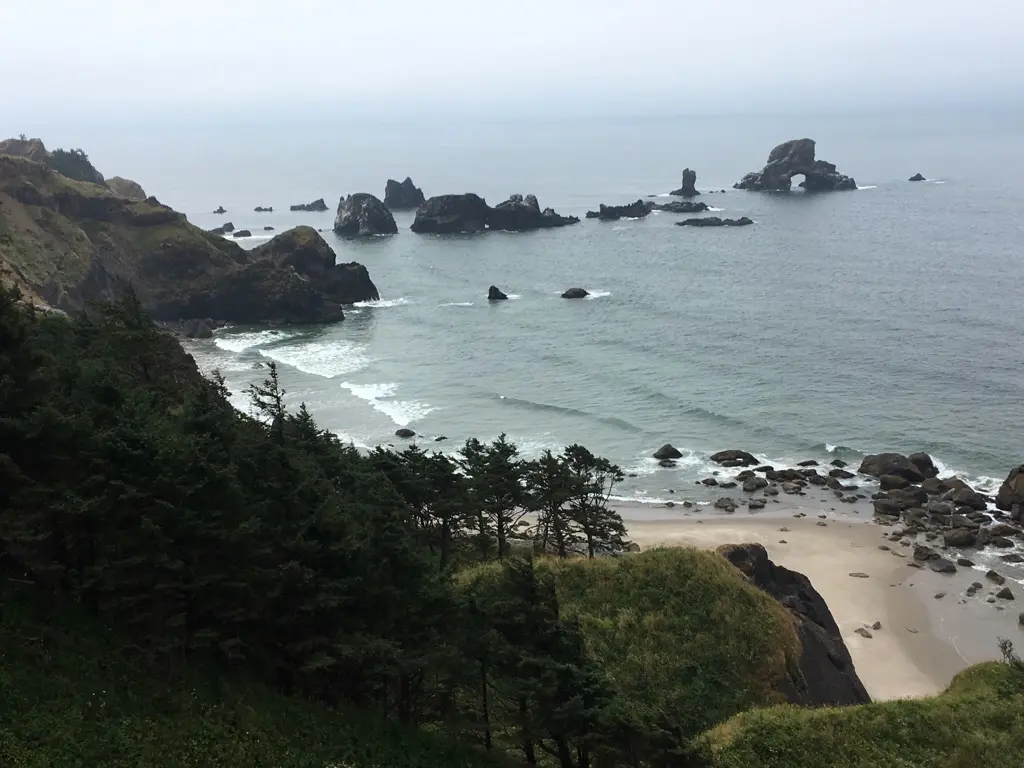 Overcast view of a rocky coastline, sandy beach, and dark sea.