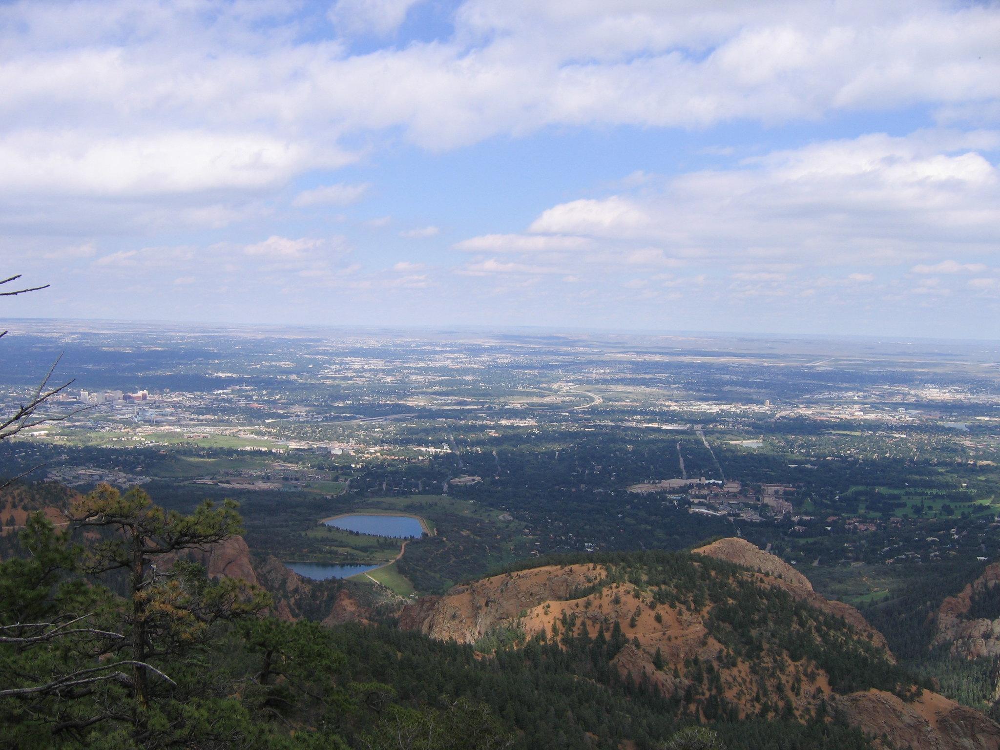 Expansive view of a valley with a distant city and two lakes.