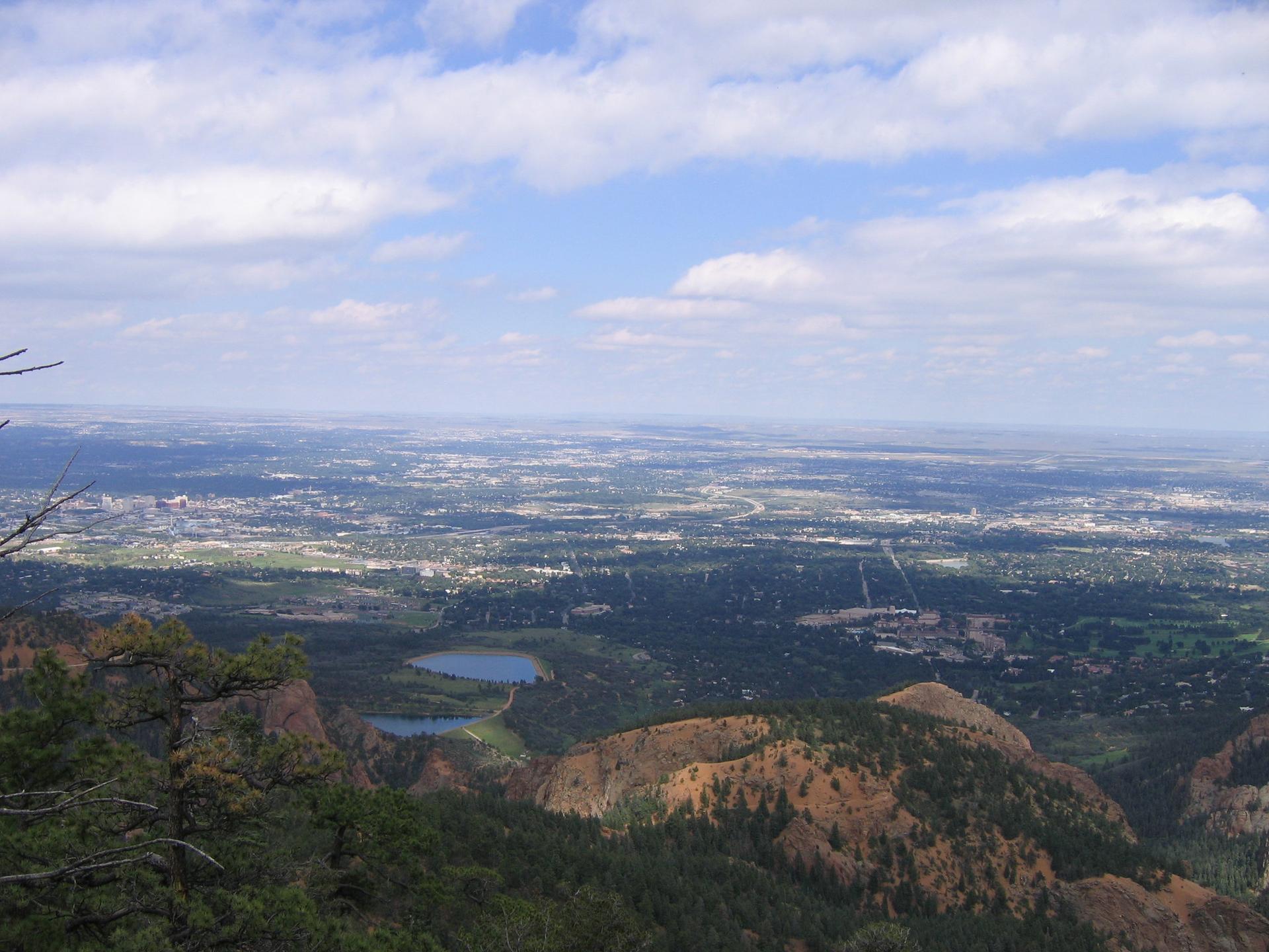 Expansive view of a valley with a distant city and two lakes.