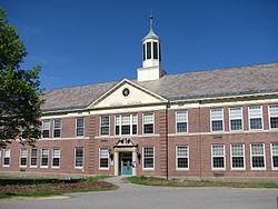 Large brick building with a white cupola under a clear blue sky.