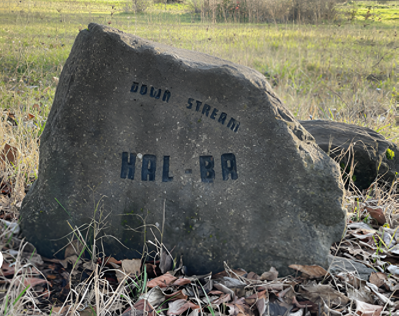 Large gray rock with "DOWN STREAM" and "HAL-BA" carved on it.