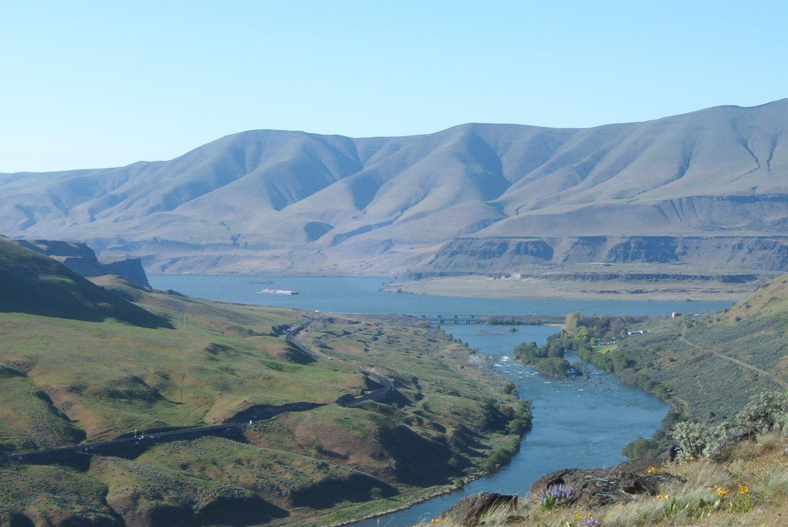 Wide river winding through a vast, arid valley with rolling hills.
