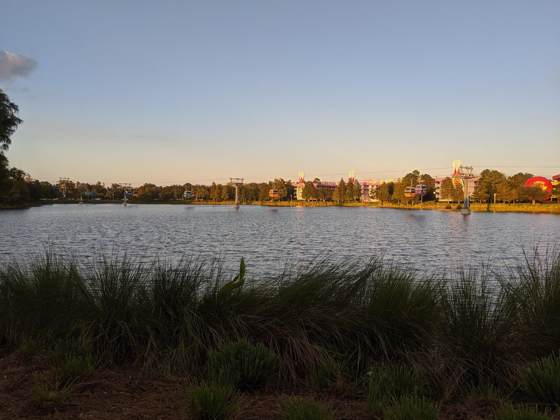 A lake at sunset with distant buildings and a transportation system.