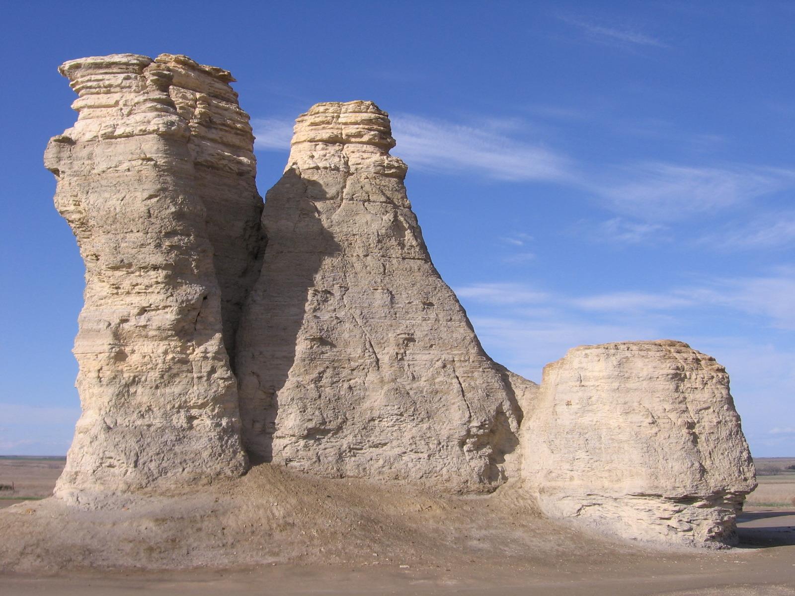 Tall, light-colored rock formations stand prominently under a bright blue sky.